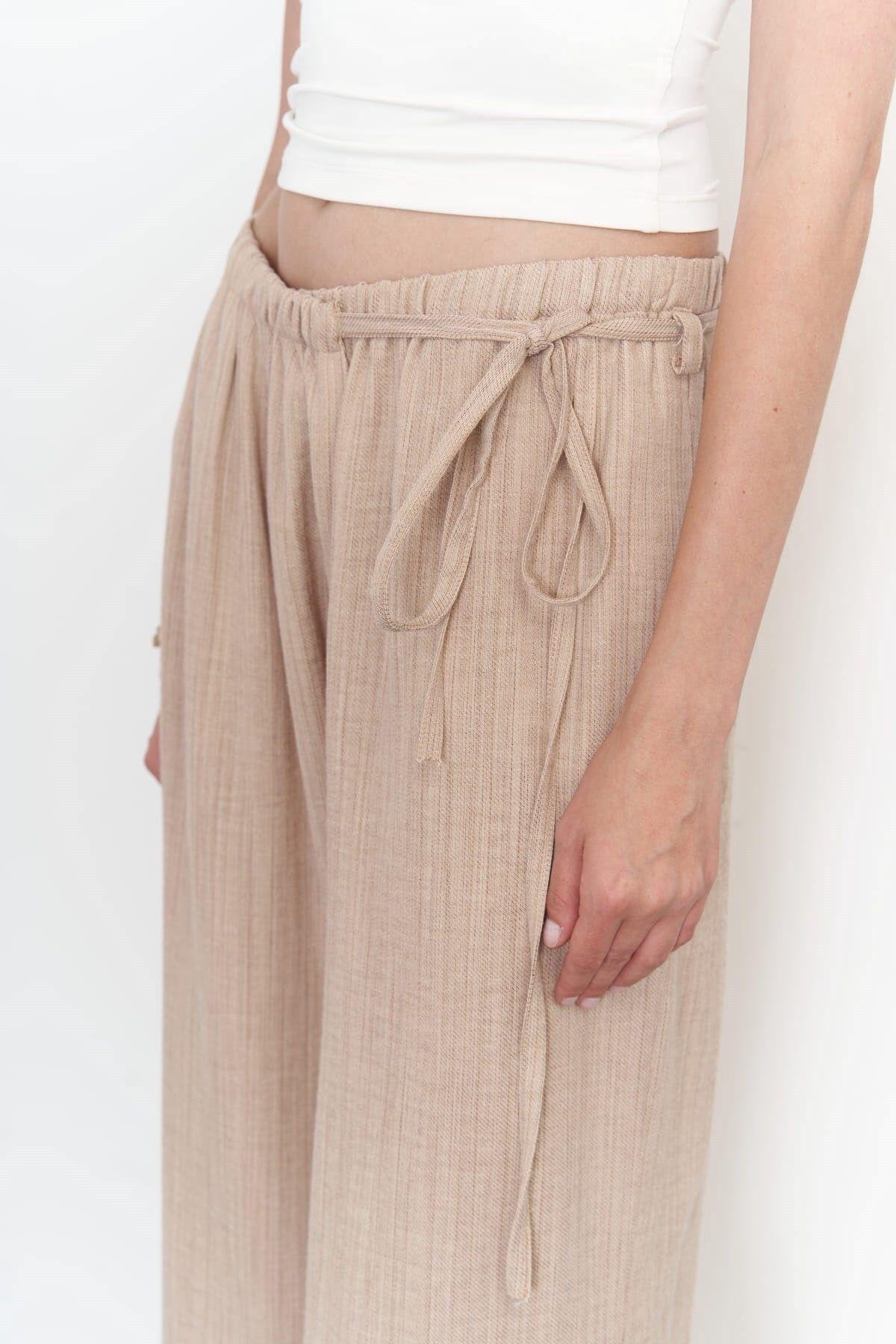 A side view of a beige wide-leg cotton-linen pants with side-tie detail
