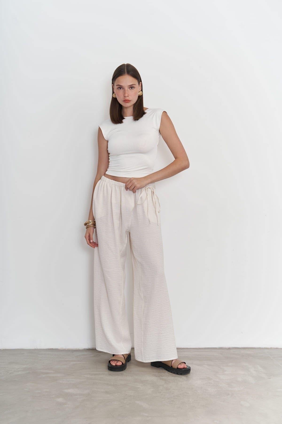 Model wearing off white wide-leg cotton-linen pants with side-tie detail