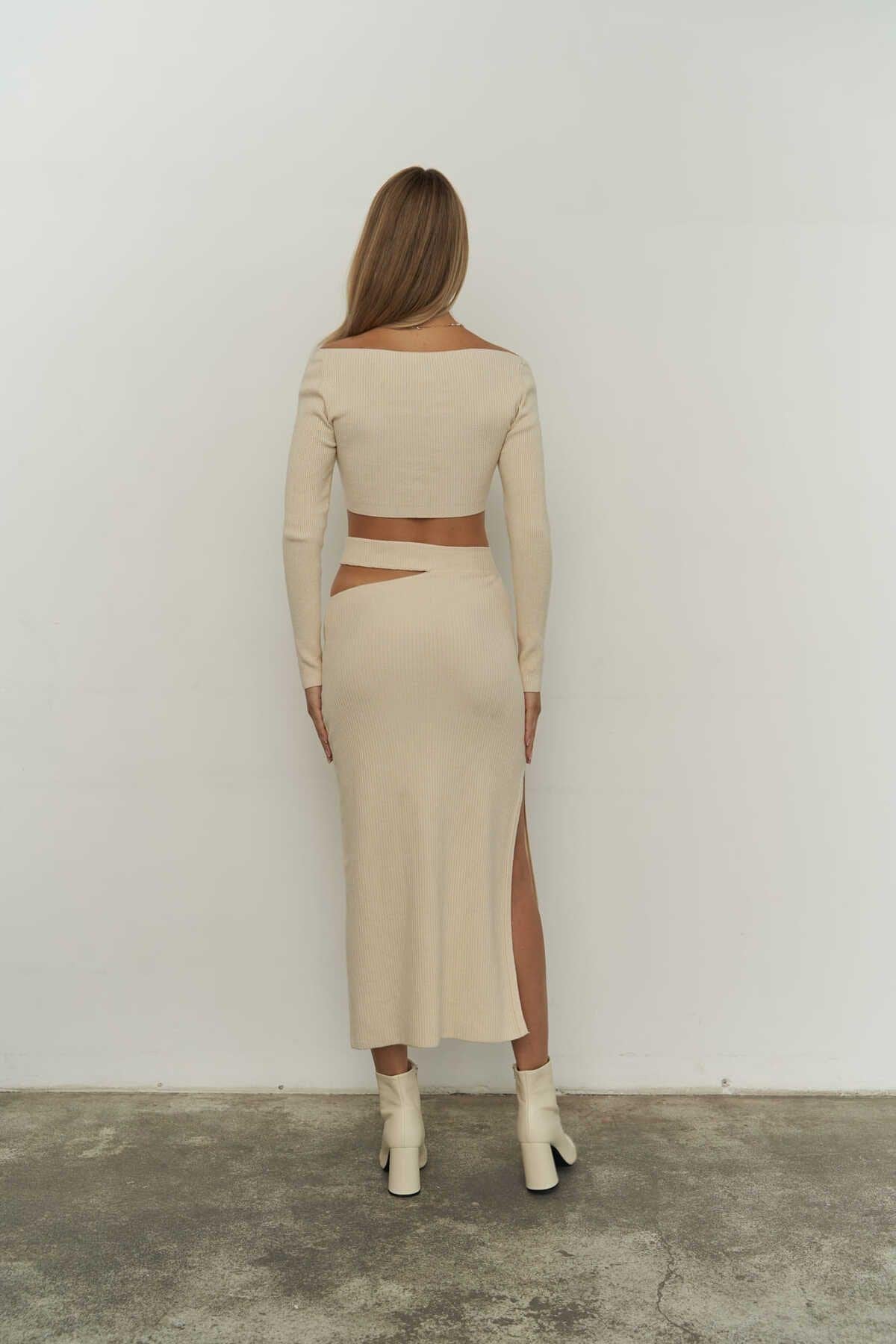 Model wearing beige knit crop top and high-slit midi skirt