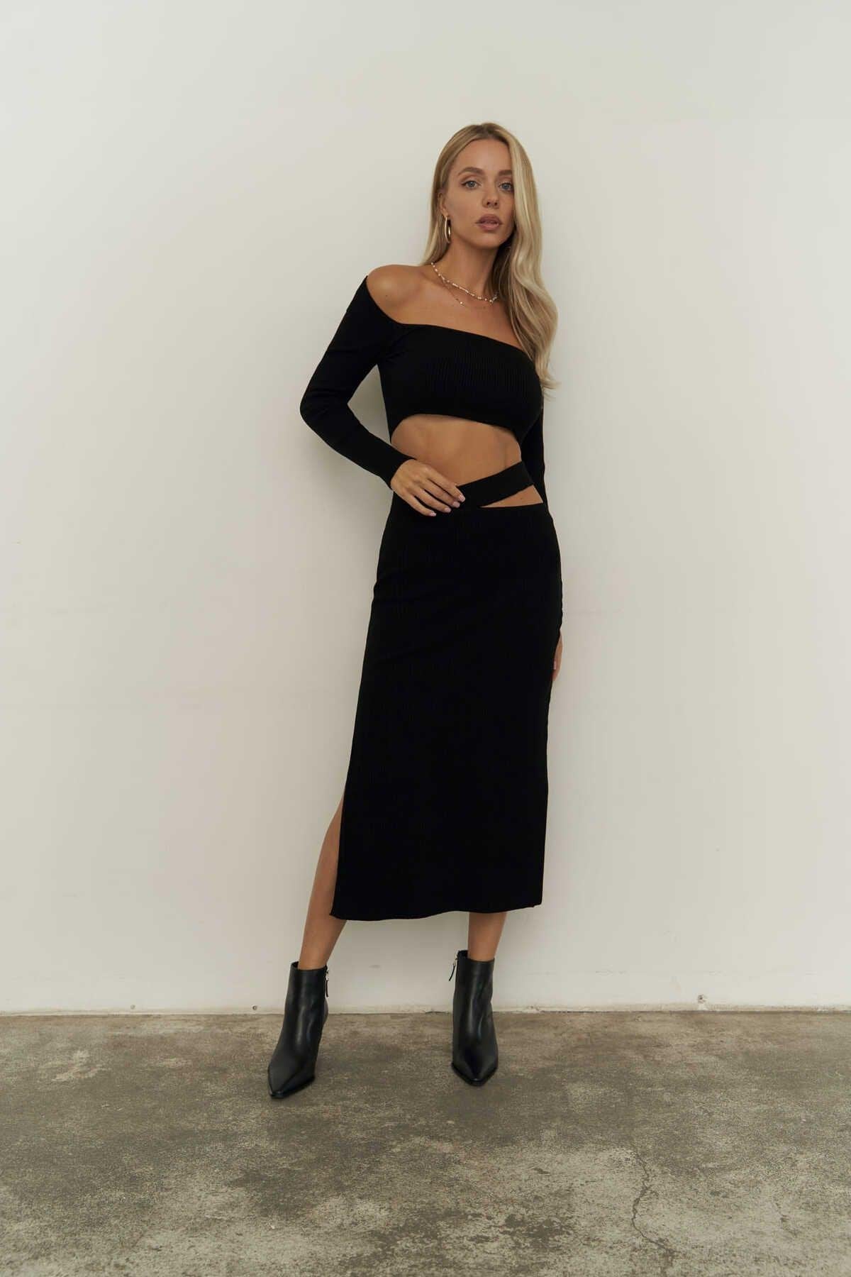 Model wearing black knit crop top and high-slit midi skirt