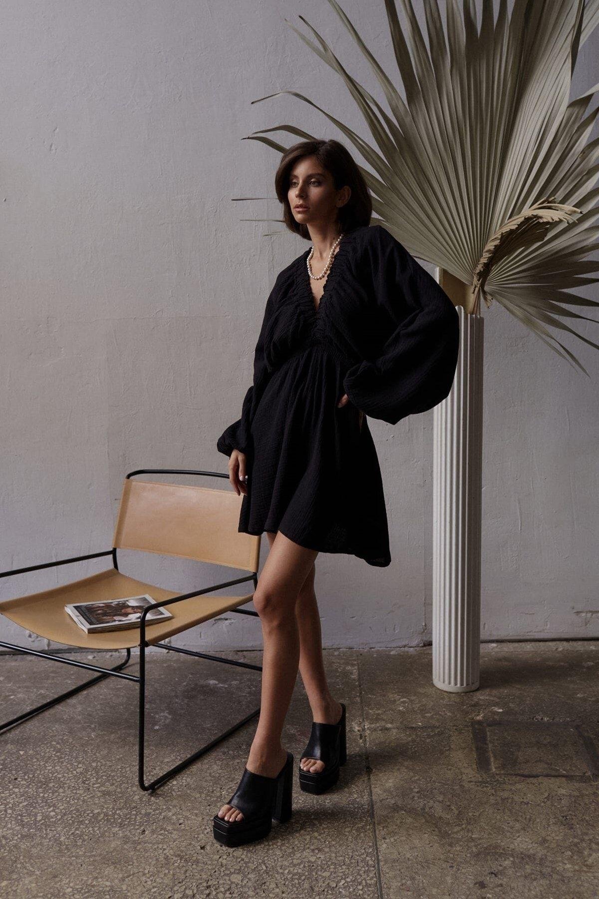 Black boho mini dress in lightweight muslin, styled with gold necklace — SHAÉN