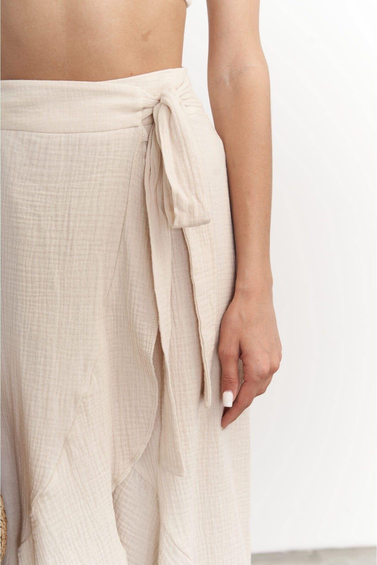 Beige muslin wrap skirt worn by a person on a white background