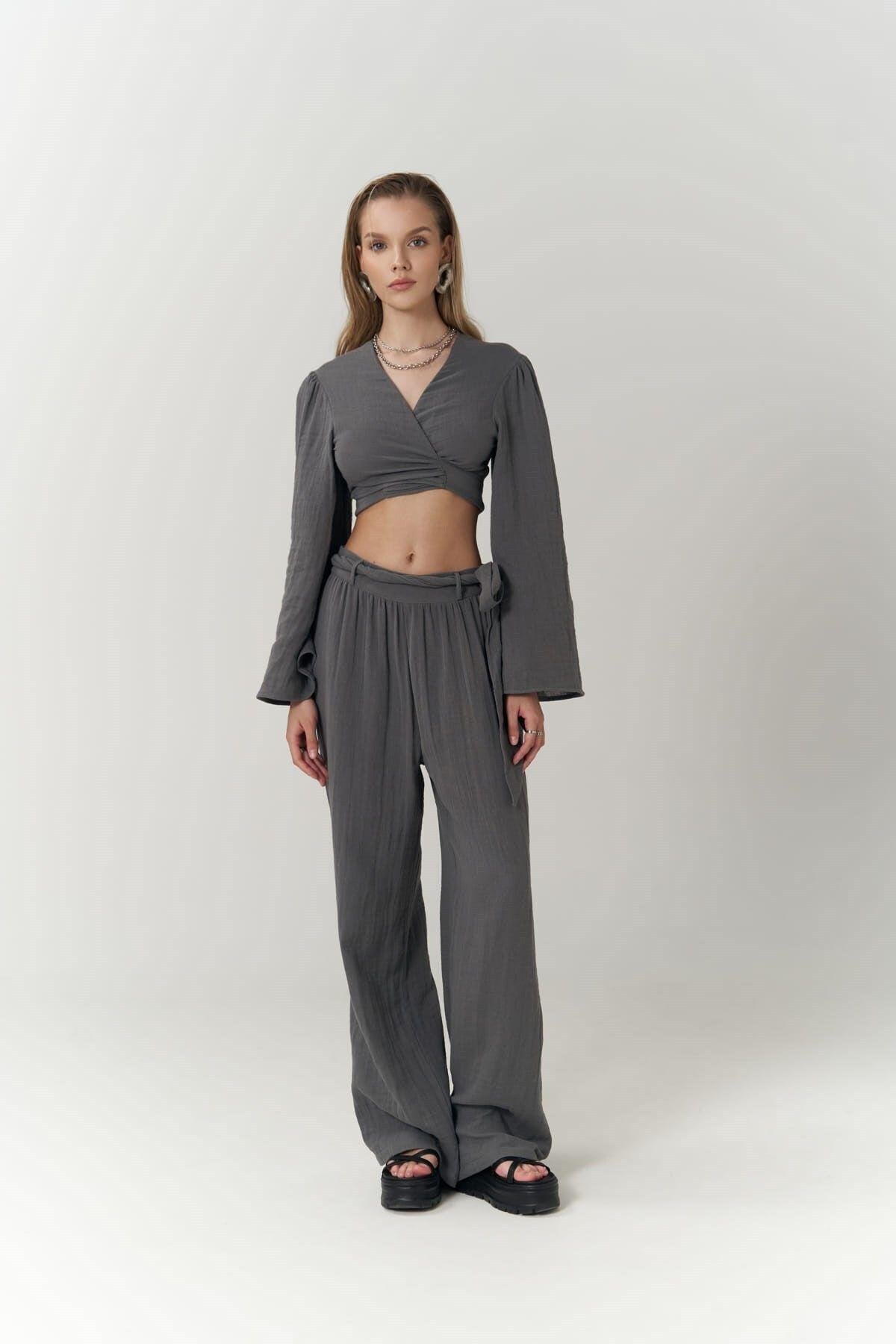Woman wearing a gray outfit with a wrap top and wide-leg pants on a white background