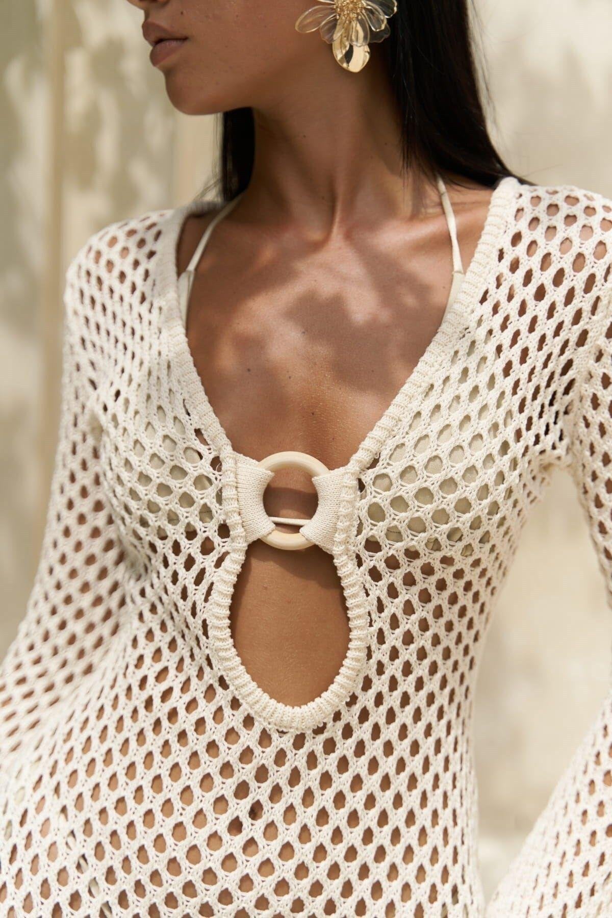 Close-up of a person wearing a white crochet top with a circular detail.