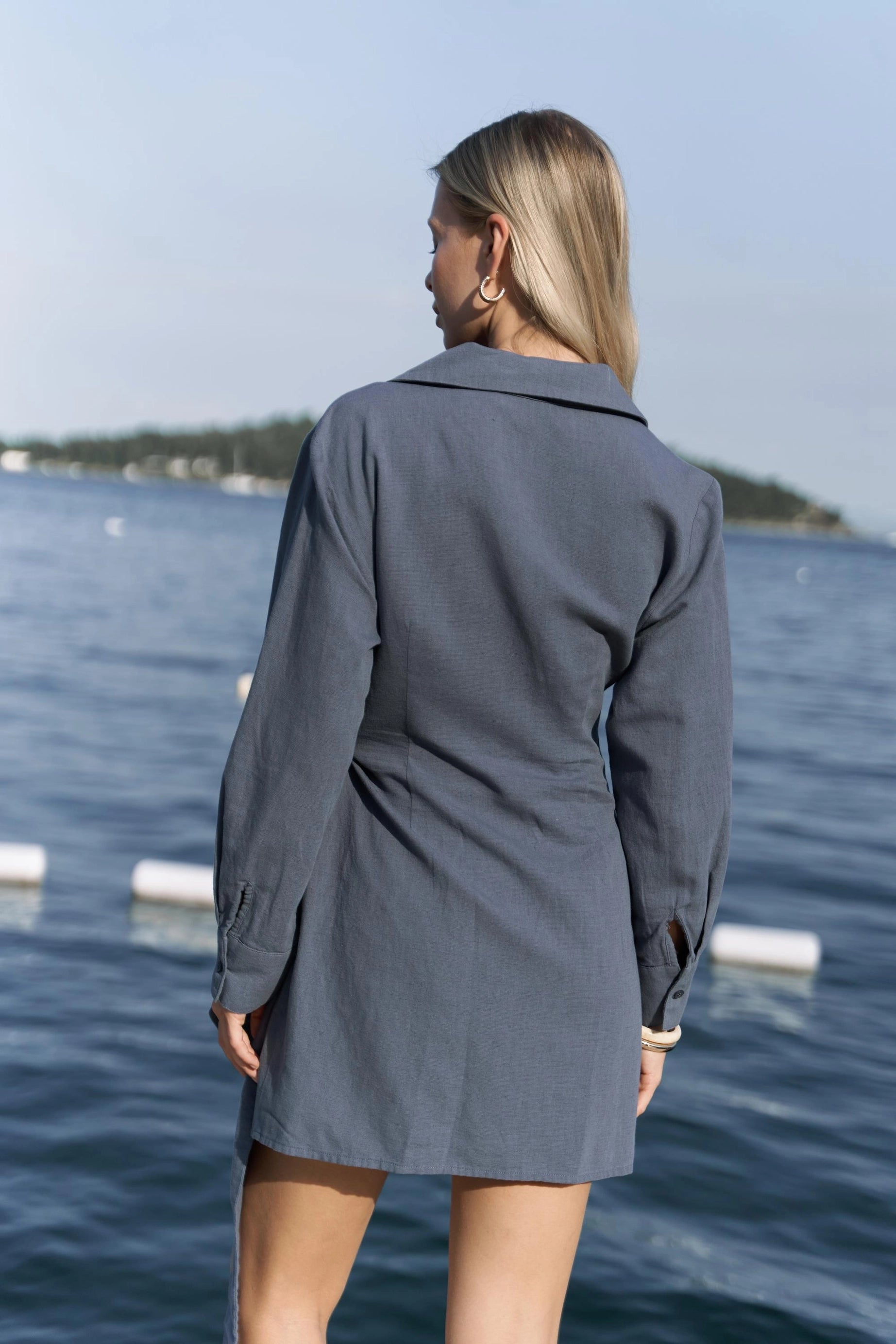 A behing view of long sleeve cotton and linen summer dress with waist tie and V-neck