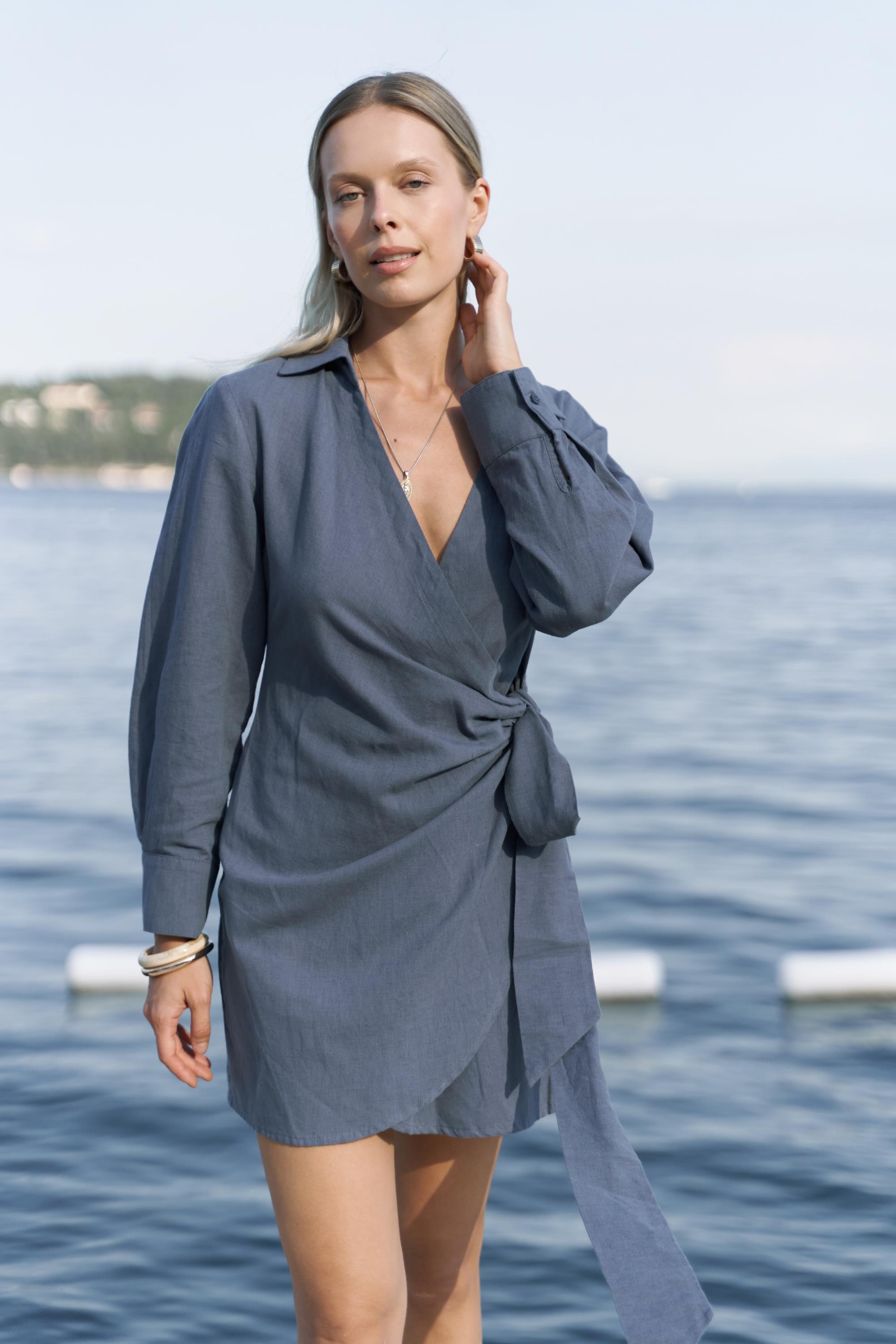 Woman wearing a blue dress standing by a body of water