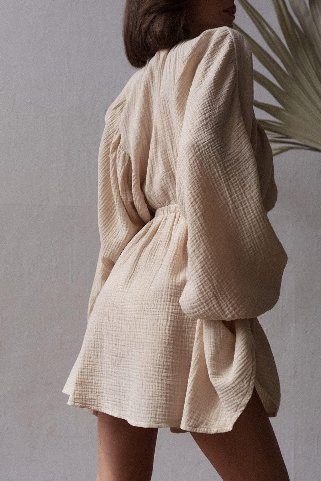 Close-up of muslin cotton dress with long balloon sleeves and cinched waist