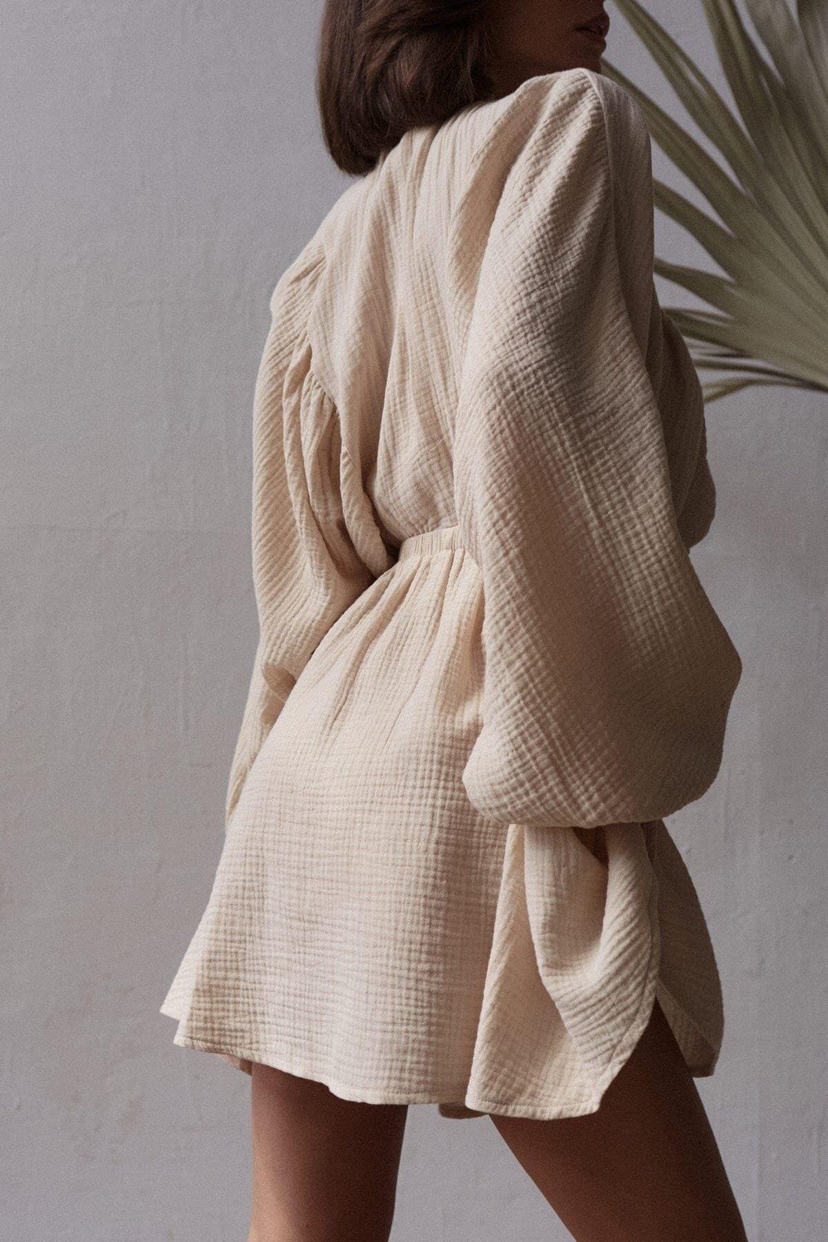 Close-up of muslin cotton dress with long balloon sleeves and cinched waist