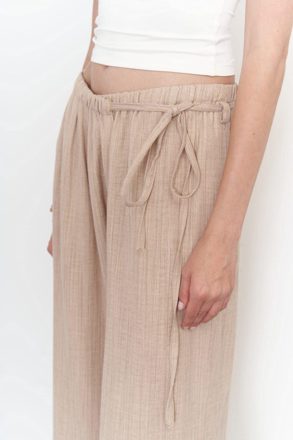 A side view of a beige wide-leg cotton-linen pants with side-tie detail