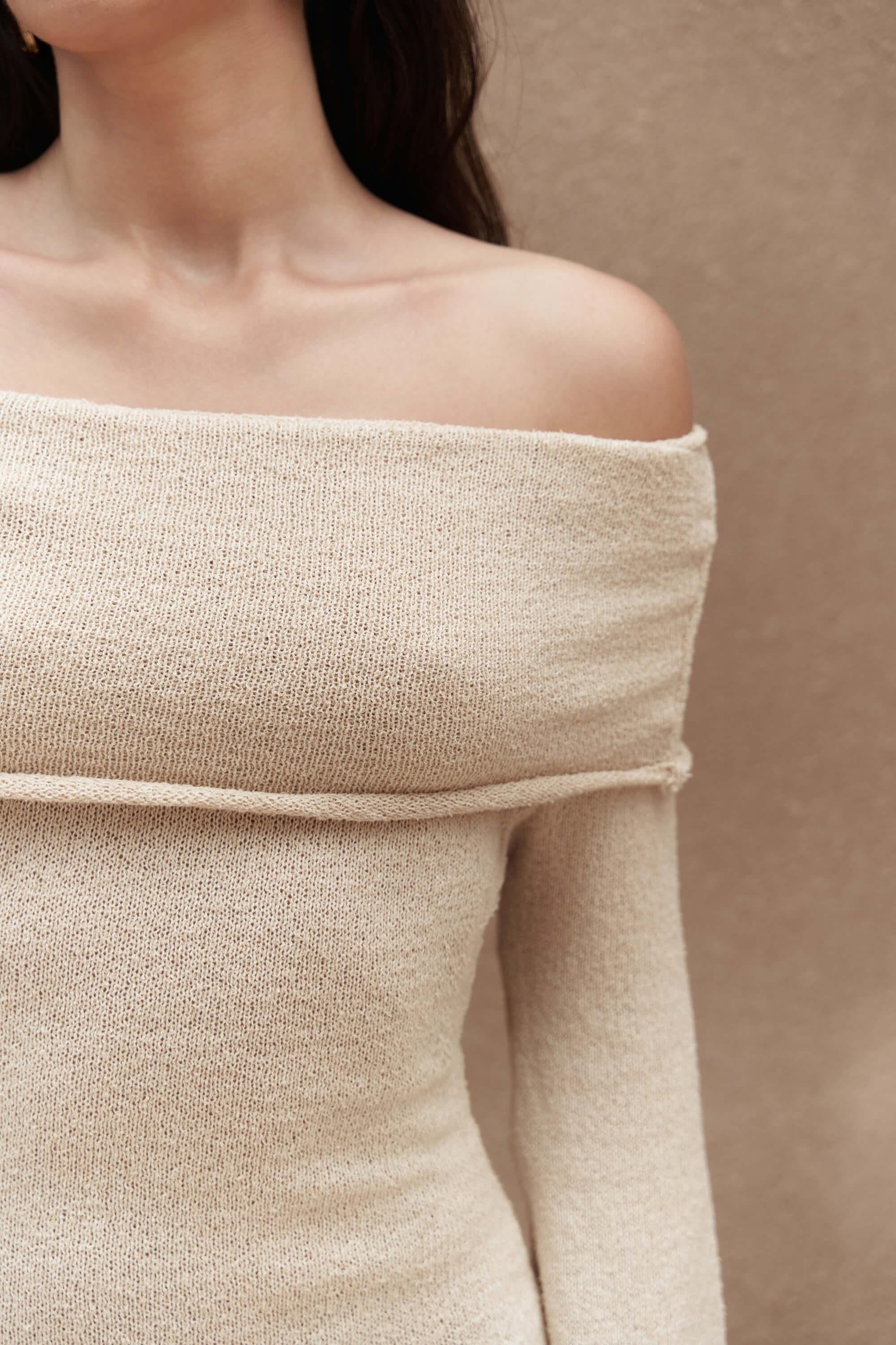 Beige off-shoulder cotton knit top worn by a person on a beige background