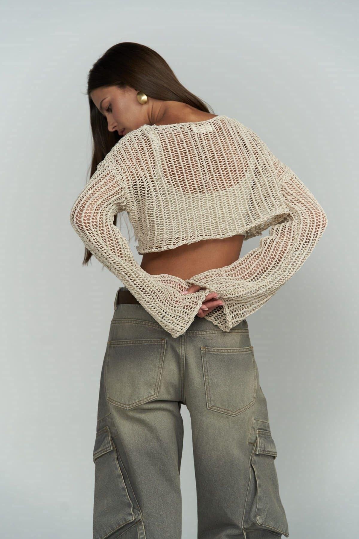 Person wearing a beige knitted crochet and green cargo pants on a plain background