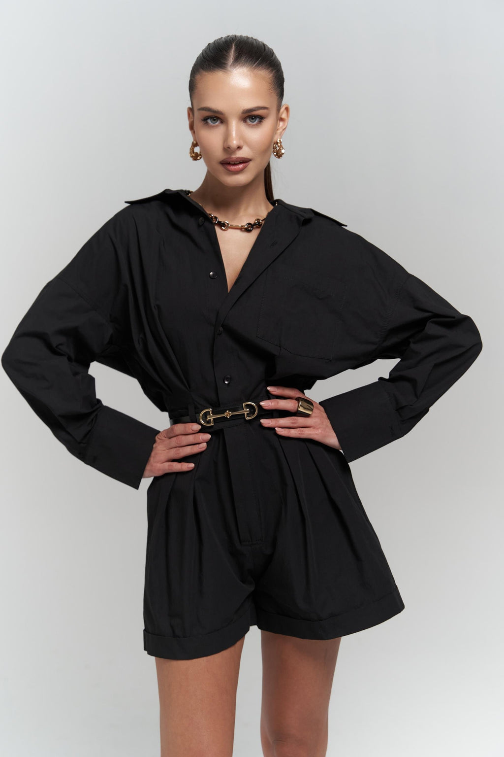 Woman wearing a black cotton romper with a belt on a white background