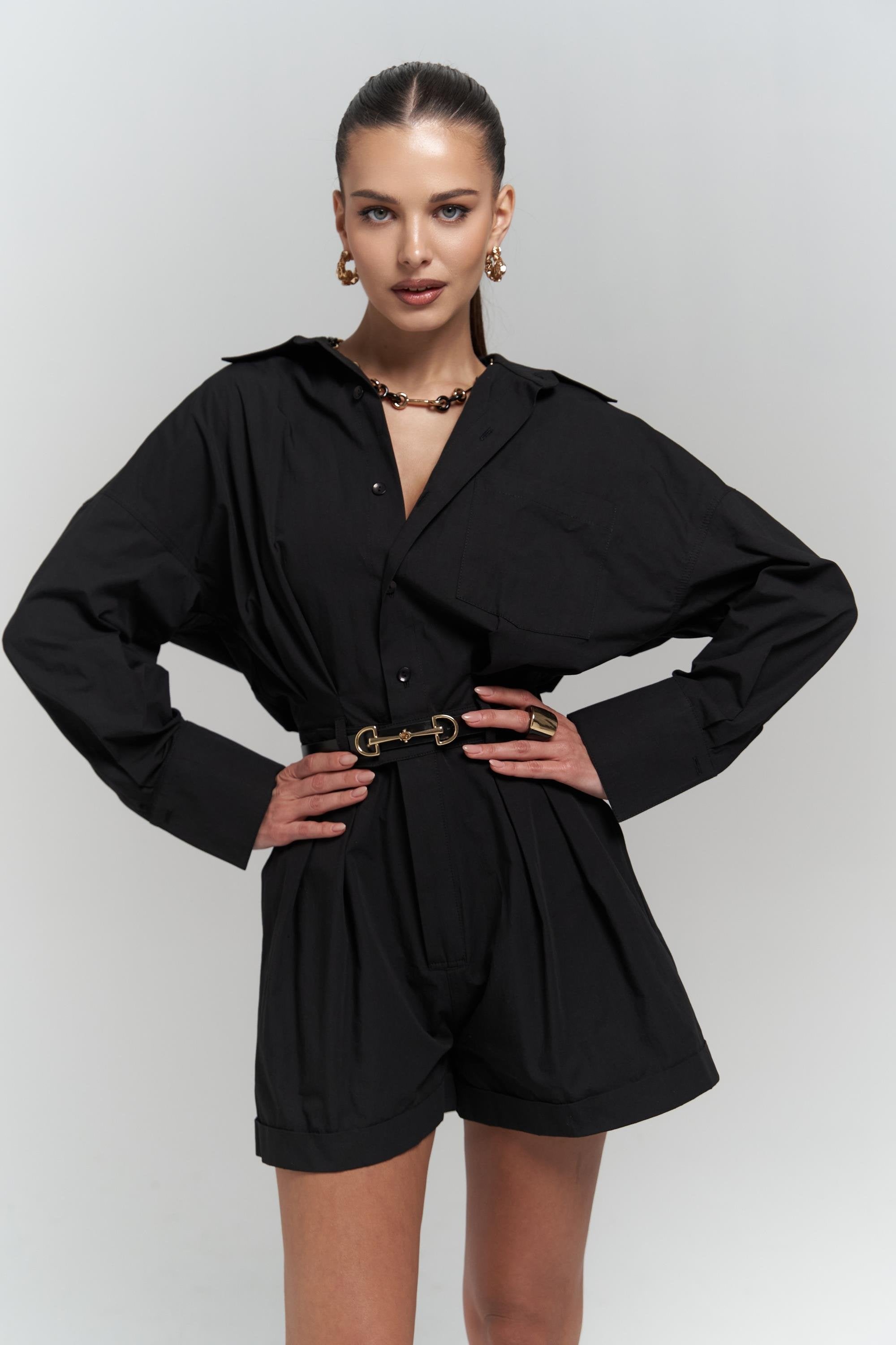 Woman wearing a black cotton romper with a belt on a white background