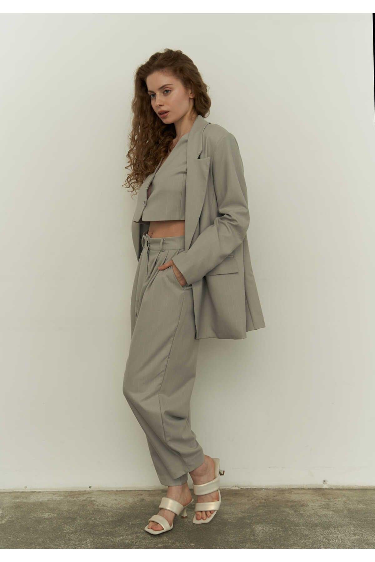 Woman wearing a gray blazer set standing against a white wall